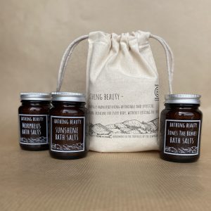 Unbleached Fairtrade Organic Cotton Gift Bag, featuring original line drawing of the Clwydian Range. Next to it are 3 amber glass Powder Jars, each containing a different bath salt from Bathing Beauty's Range